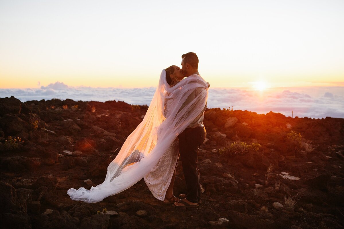 A bride and groom kiss during sunset at the summit of Haleakala National Park