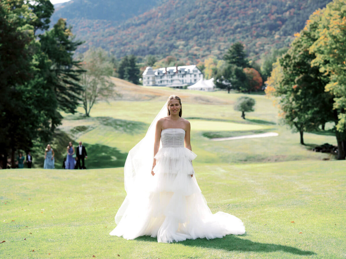 The bride is walking at The Ausable Club's golf course in New York. Image by Jenny Fu Studio.