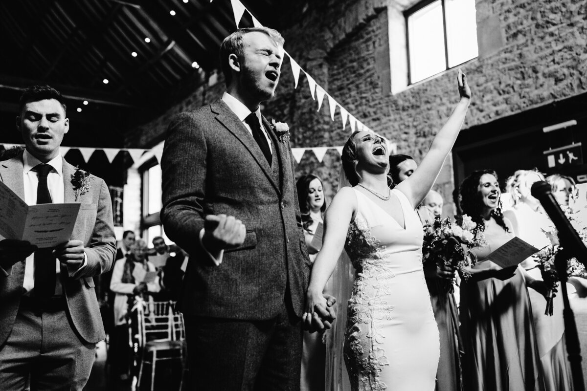Black and white photo of Bride and Groom singing and walking down aisle