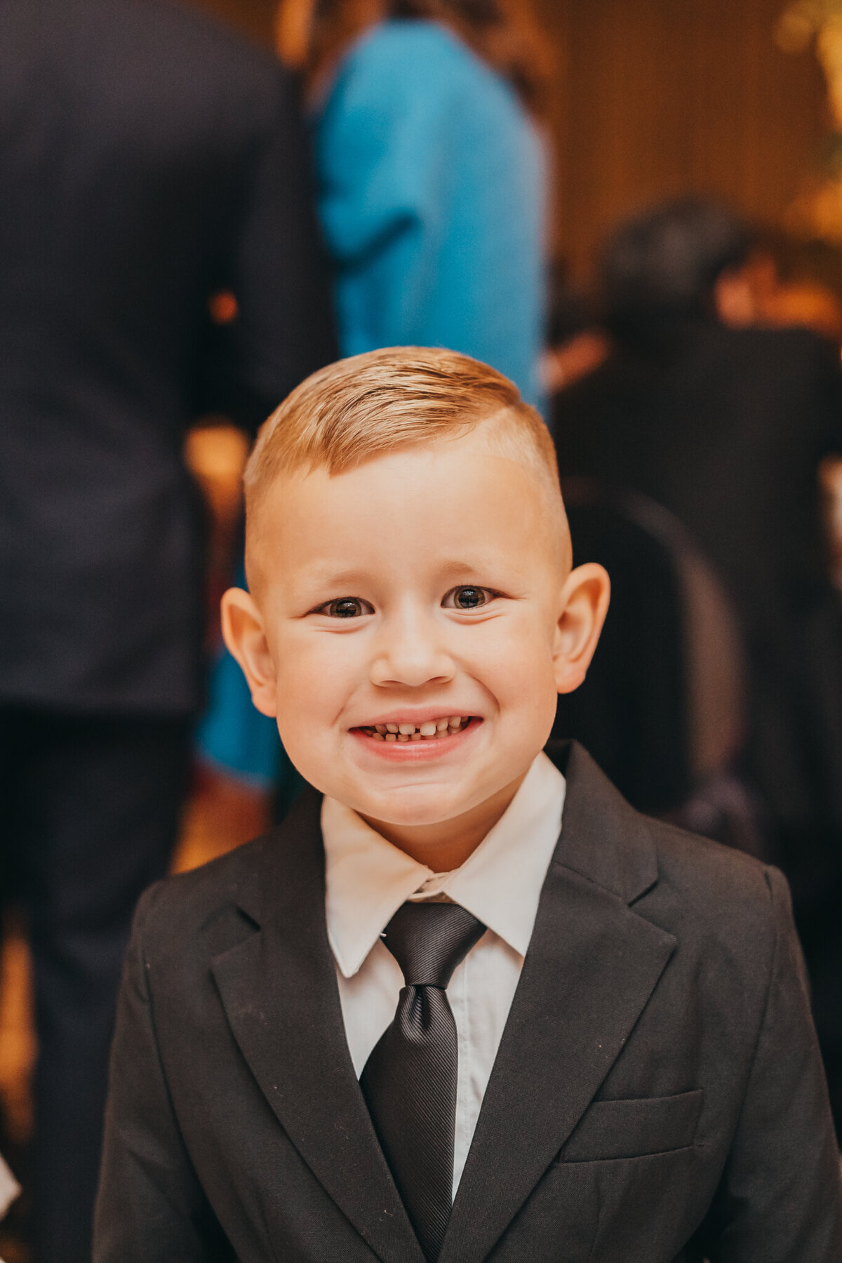 little boy smiles at the camera  wearing a fitted tux