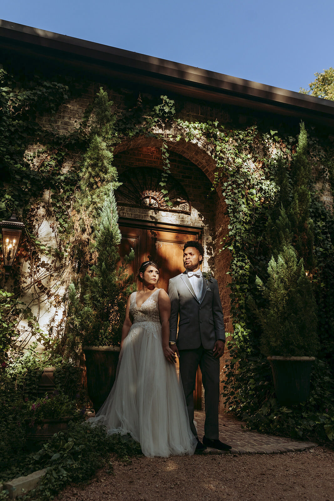 Bride and groom in striking pose side by side standing in sunlight ligh