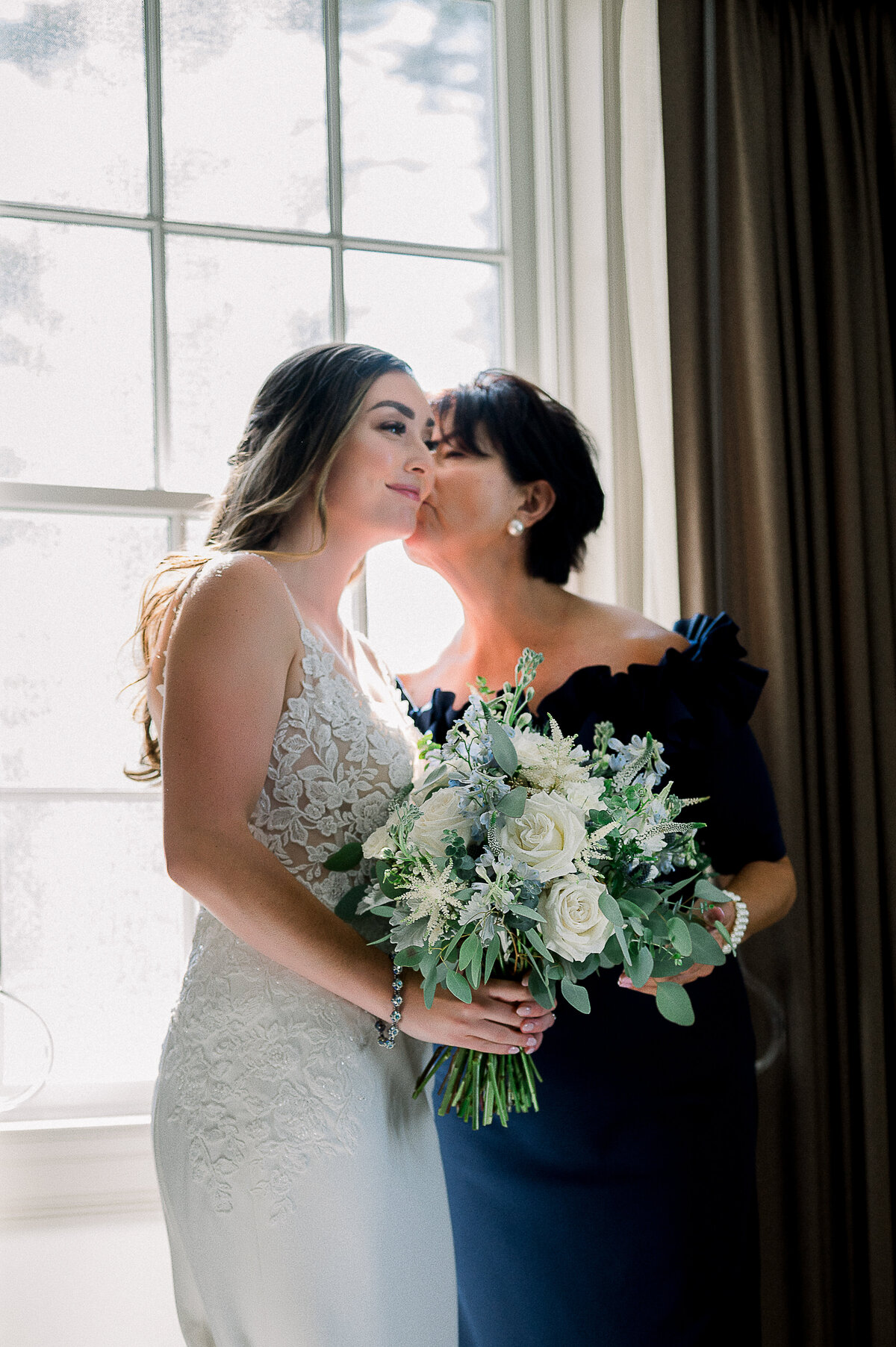 woman kissing the bride on the cheek