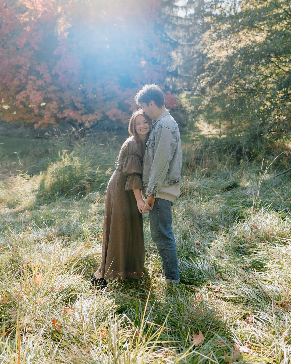 A couple laughs and runs through a field during their playful engagement session in Spokane, Washington, highlighting joy and spontaneity.