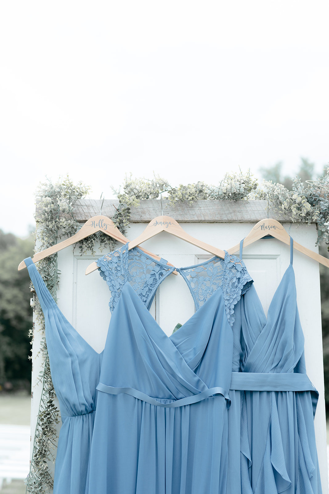 Light Blue Bridesmaid Dresses hanging off White Barn Door at Ridgetop in Prescott Wisconsin