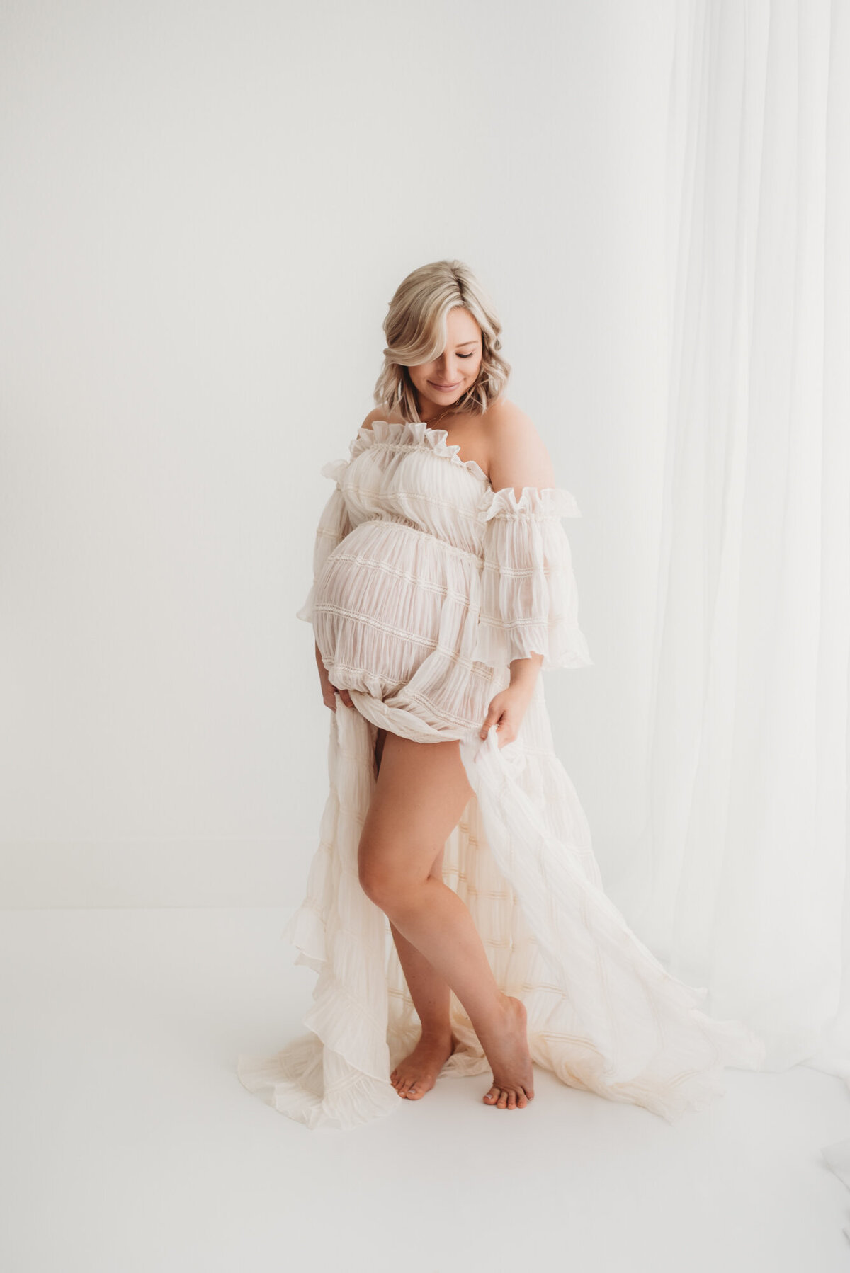 pregnant woman holding boho cream dress showing her legs