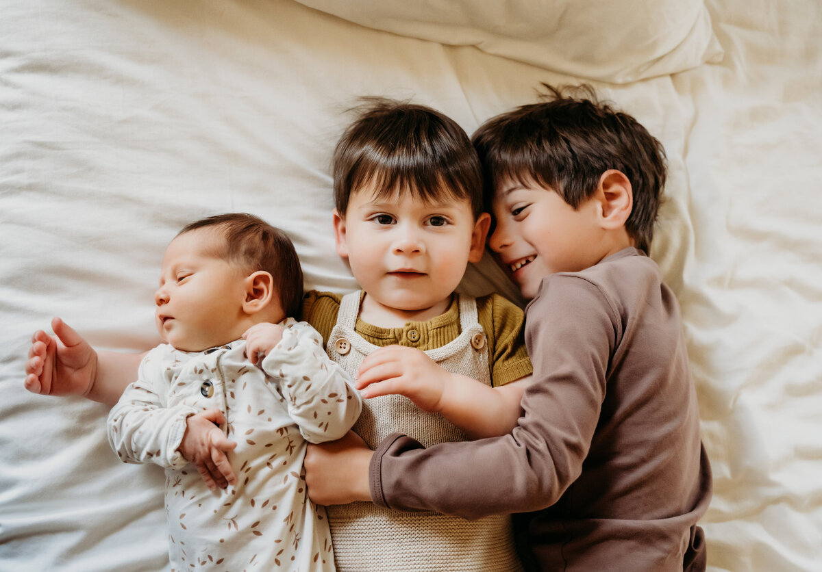 Newborn Photographer,  two brothers lay down next to their baby brother