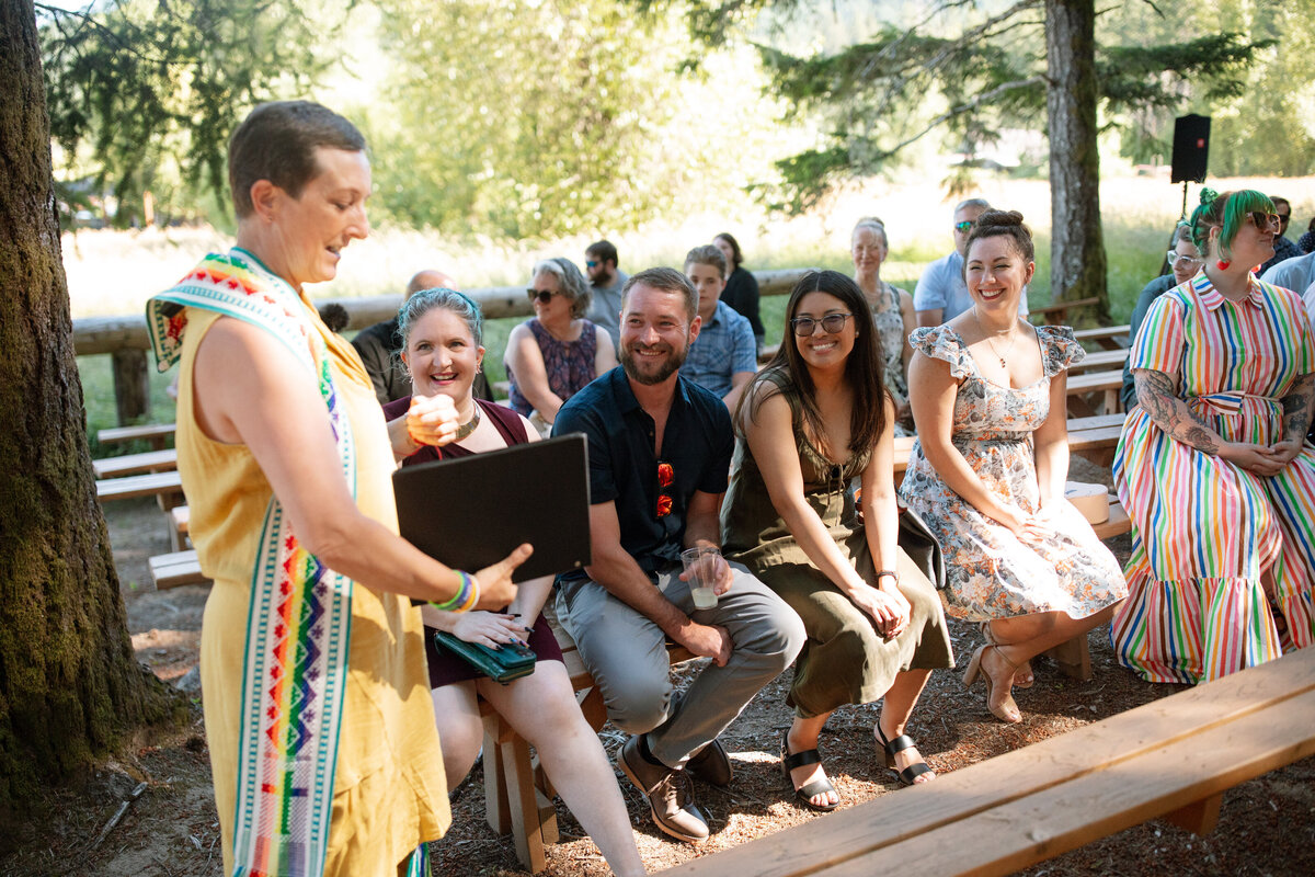 Officiant walking into the ceremony space with guests on bnenches.
