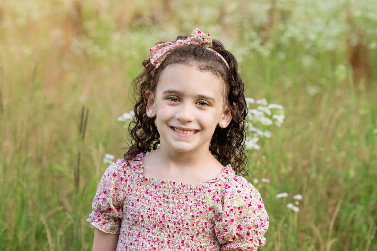 happy girl in floral dress smiles in flower field