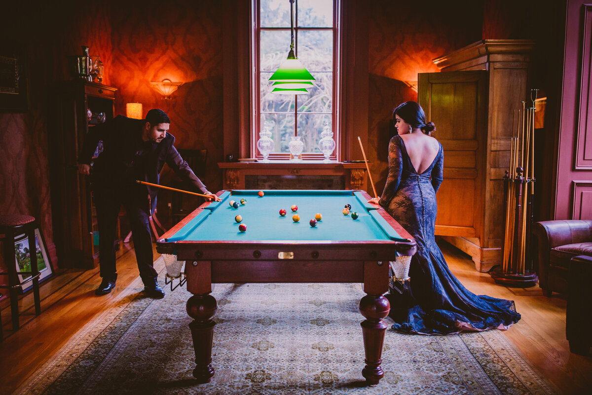 A couple in black formal outfits playing billiards pool at the villa nuits mansion in new york