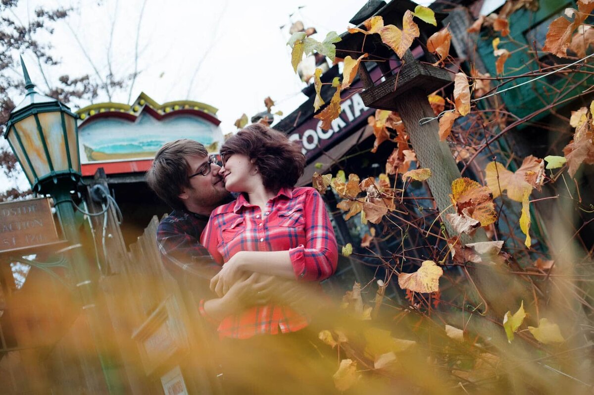 a couple hug together in front of their favorite bar during their engagement session in portland