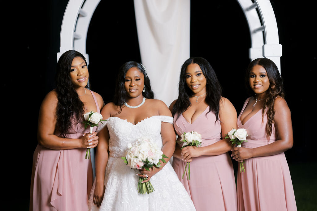 bride standing with bridesmaids in pink dresses