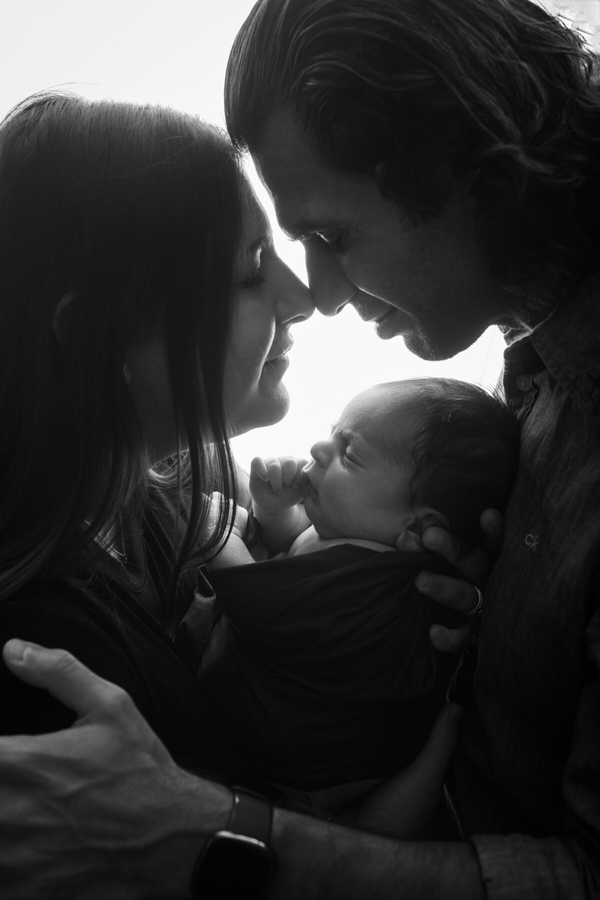 black and white backlit close up of mom dad and newborn