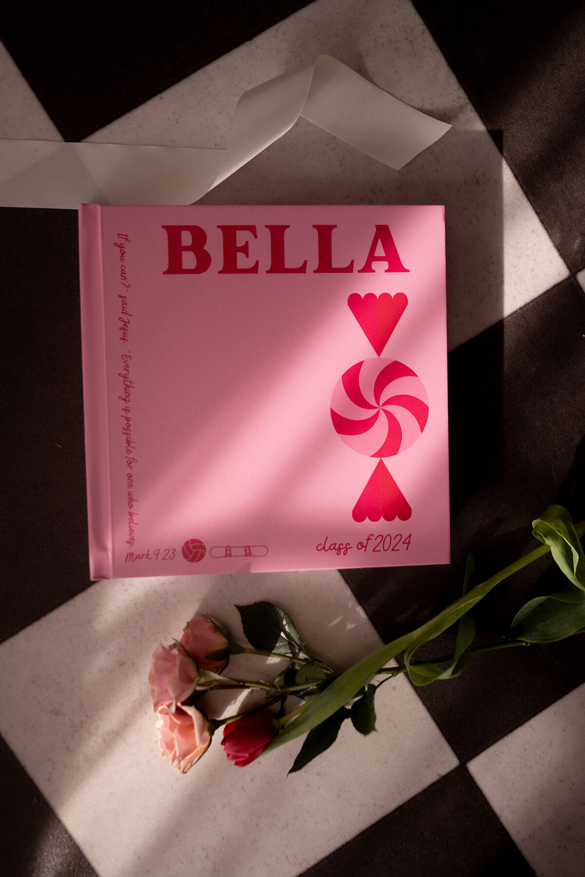 A pink fine art photo album laying on tile with roses