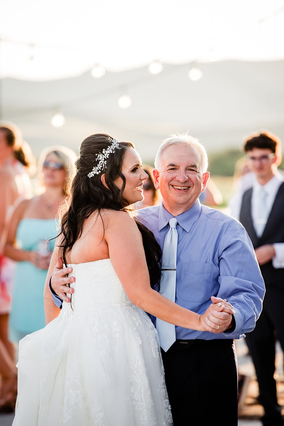 Father of the bride smiling at the camera as he dances with his daughter on her wedding day