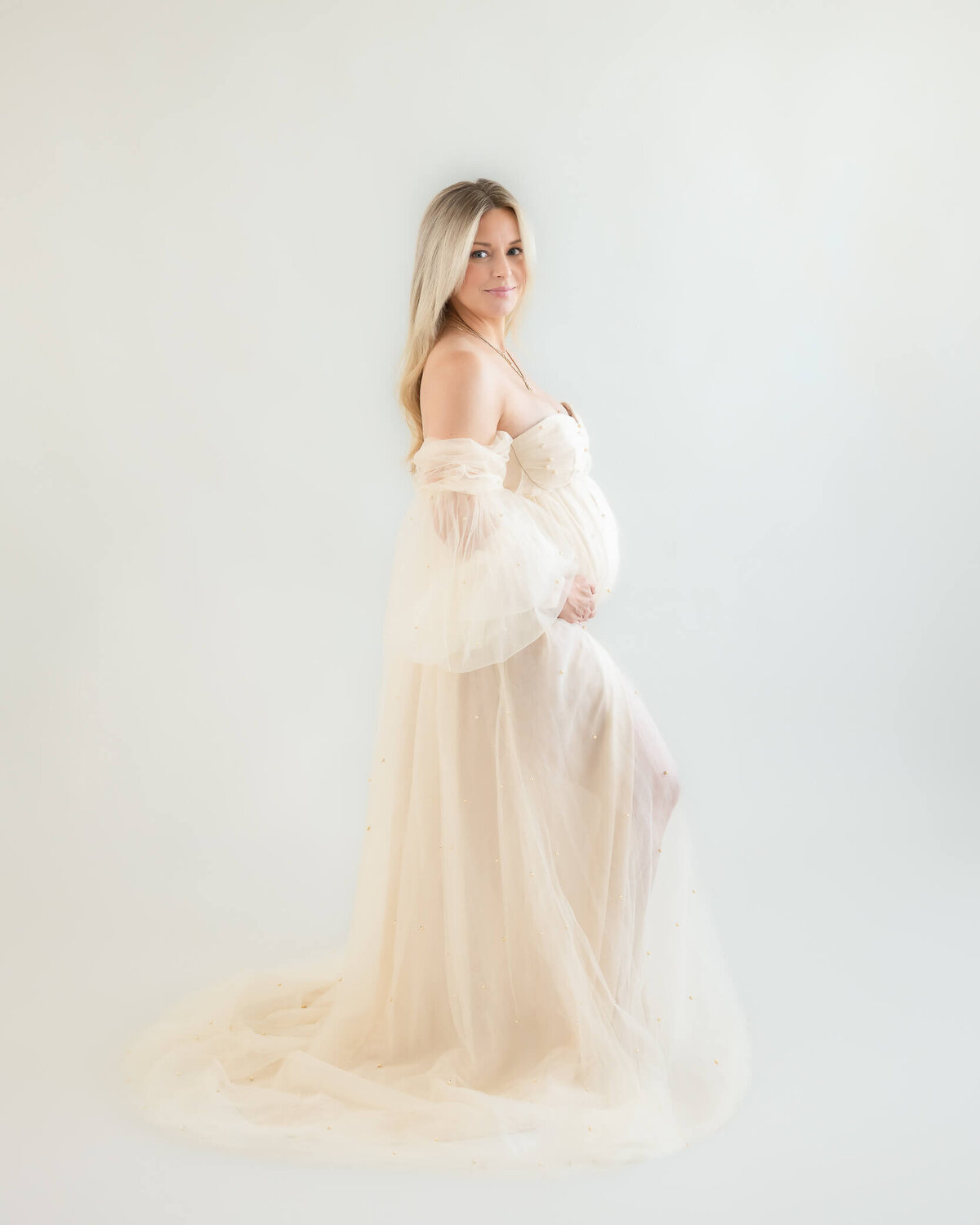 In studio portrait of beautiful preganat woman in goregous off white dress on an offwhite background, captured by Allison Amores Photography