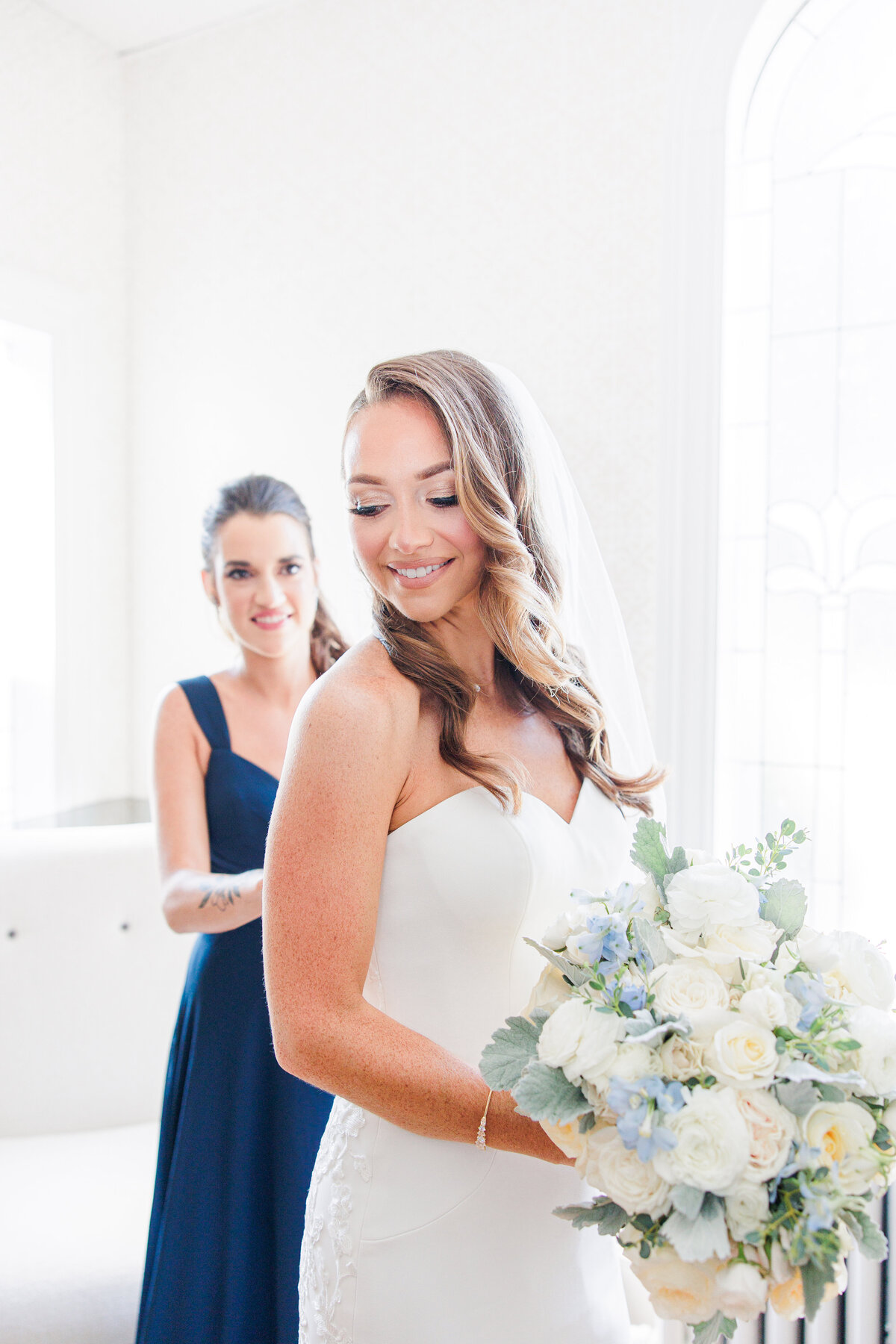 Bridesmaid helping bride into her dress in the South Shore Country Club bridal suite