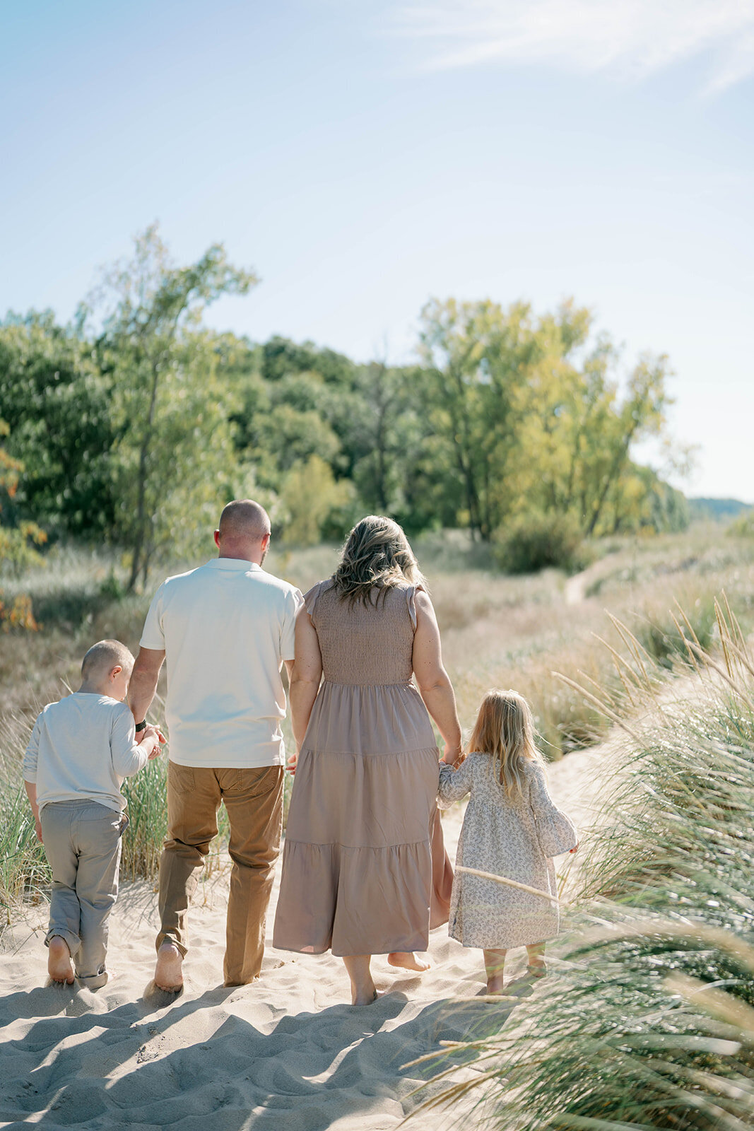 The Loza family walking together toward the shoreline at Weko Beach surrounded by dune grass.