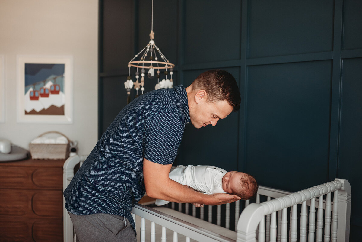 dad holding baby boy putting him to sleep in his crib