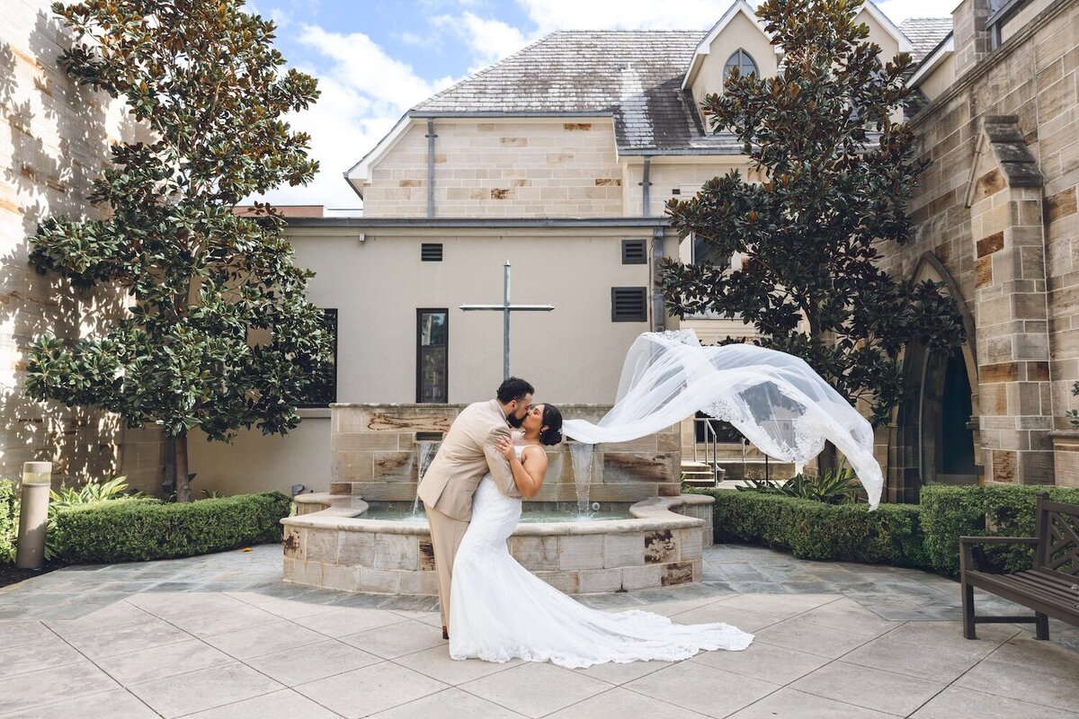 Romantic kiss with flowing veil in Houston courtyard