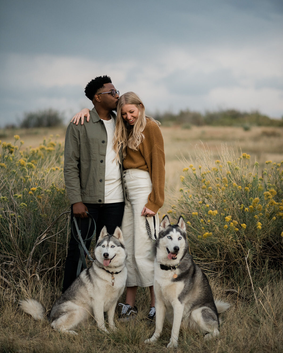 Couple smiling with their two dogs during an engagement session in Golden, Colorado