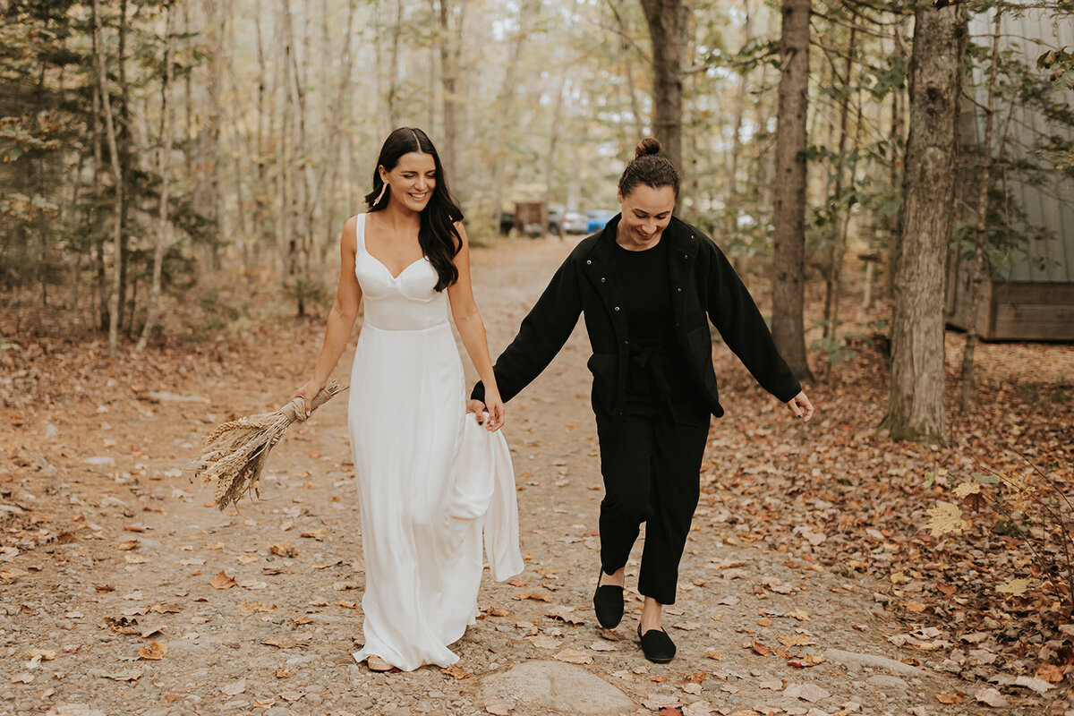 Maine couple holding hands walking in the woods with smiles after their wedding
