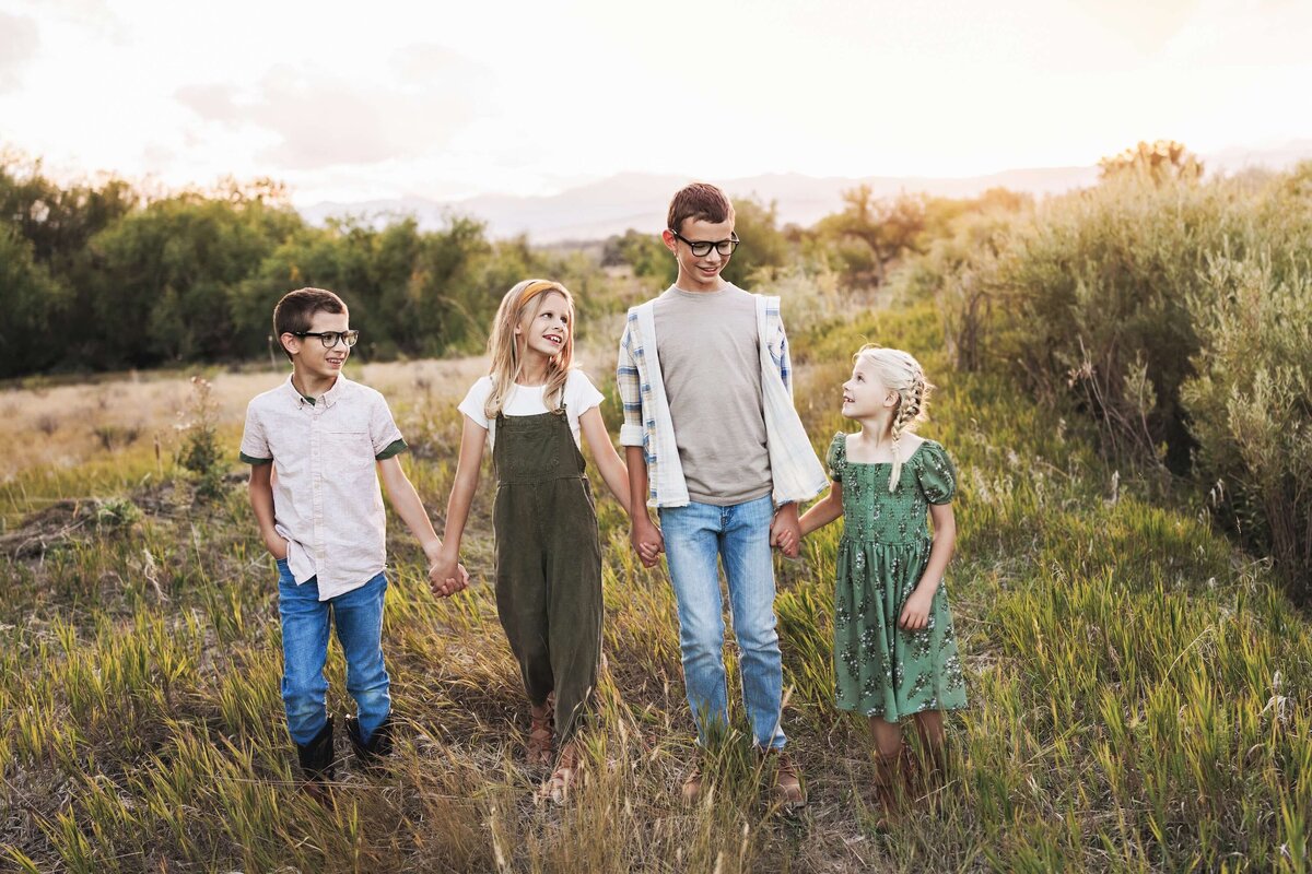 Siblings walking together in the field at their house holding hands