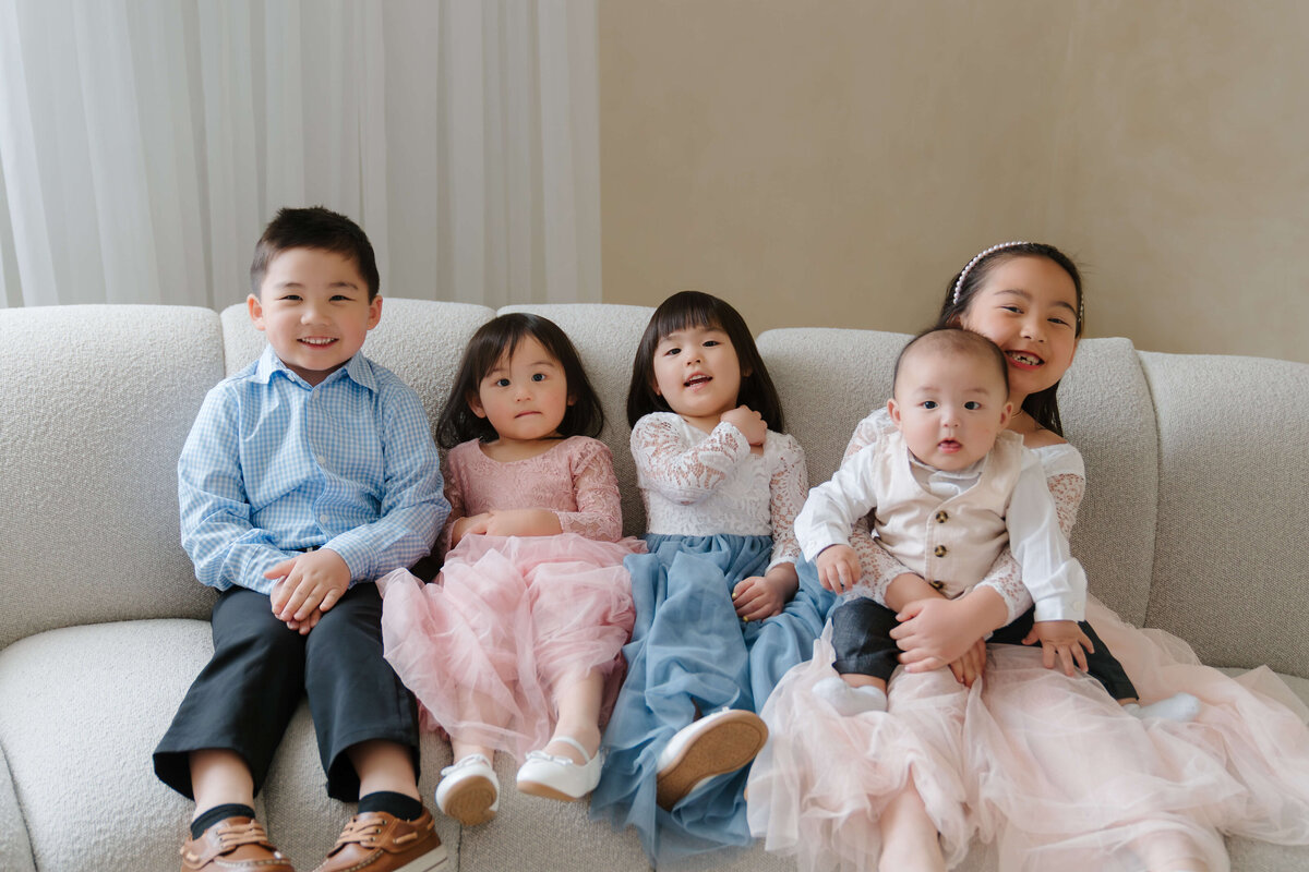 Four children relax on a plush couch in a stylish living room, surrounded by warm decor and soft lighting.