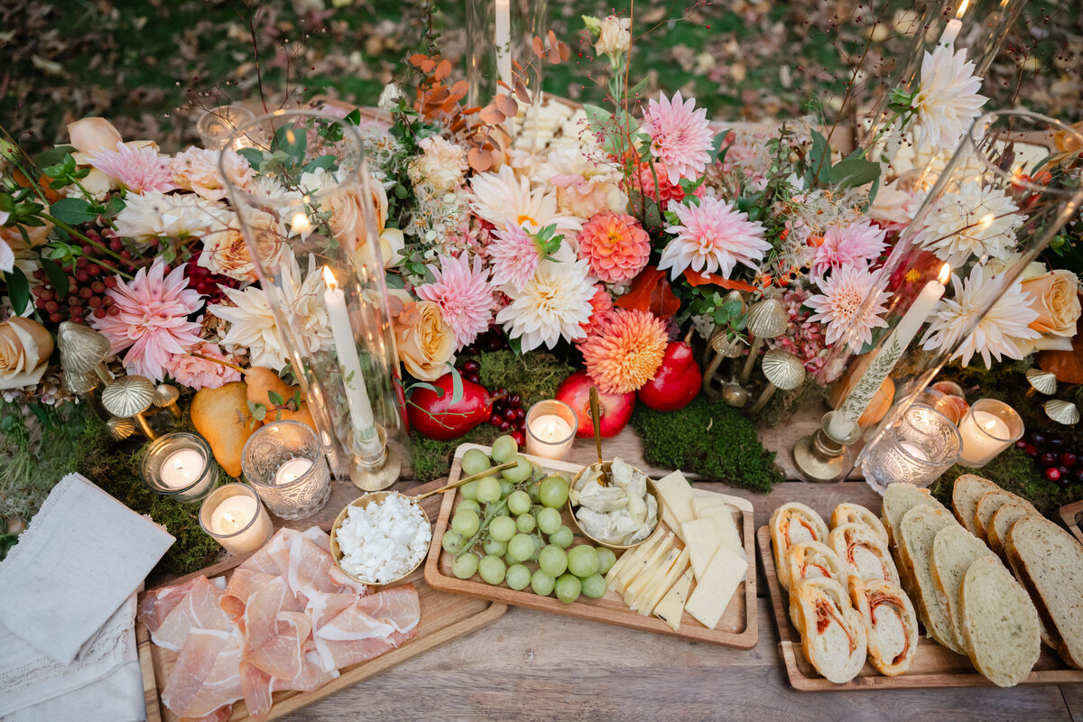Grapes and charcuterie with flower arrangement surrounding it