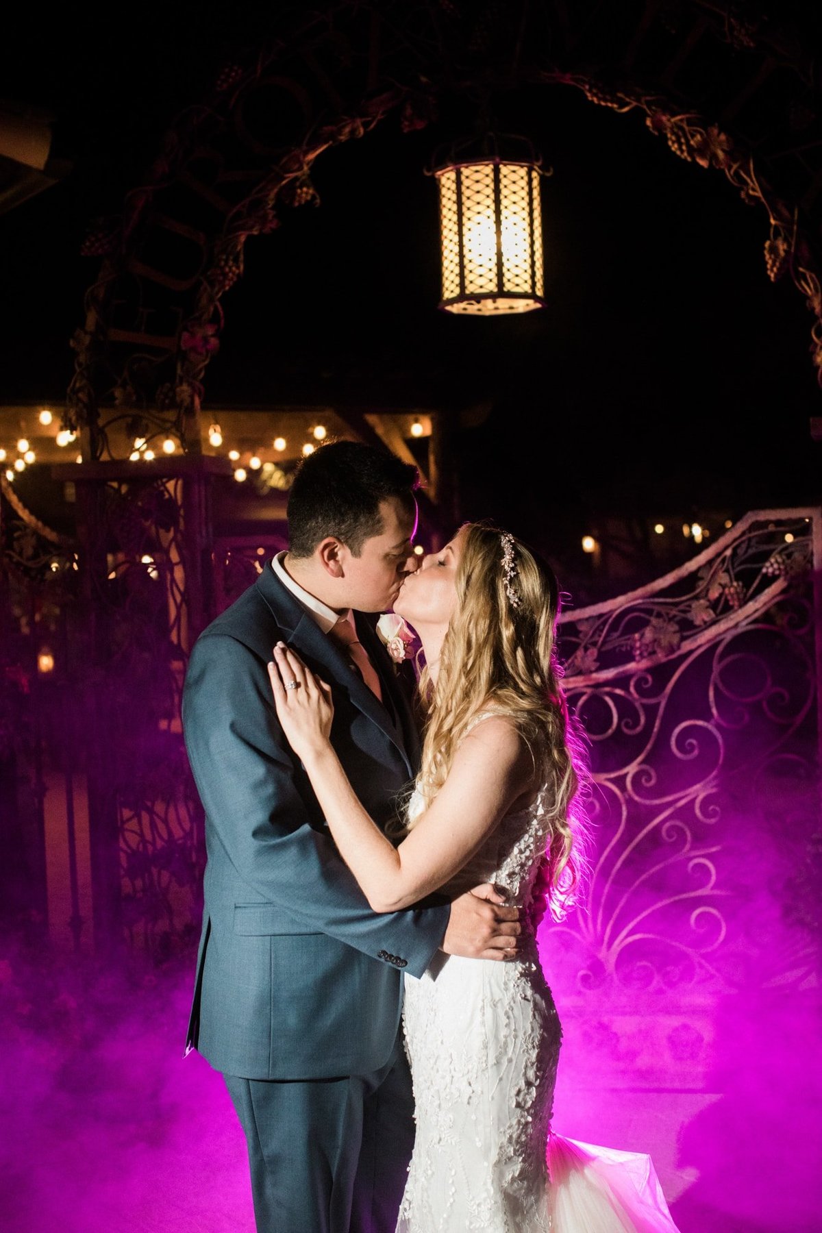 Bride and Groom share a kiss as a purple haze appears in the background