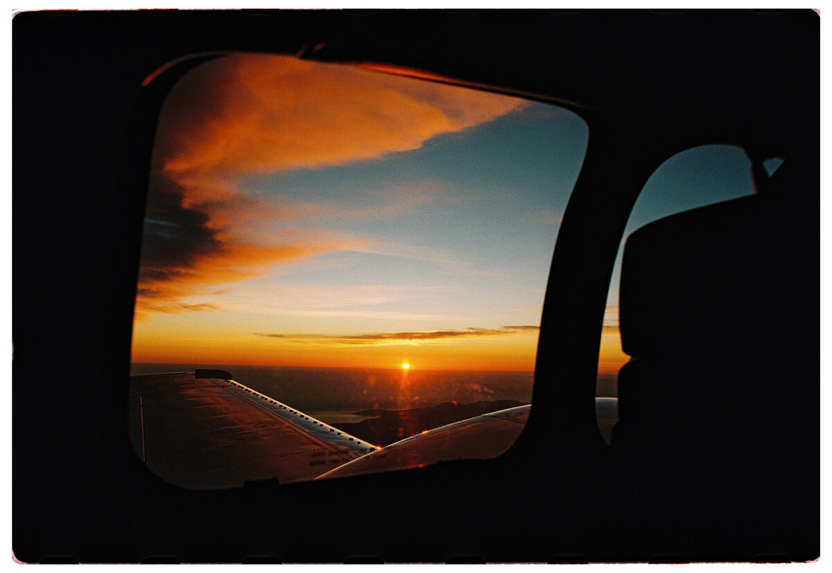 Sunset through a plane window, captured on film by Kate Winters Photography, showcasing an authentic moment in a documentary style.
