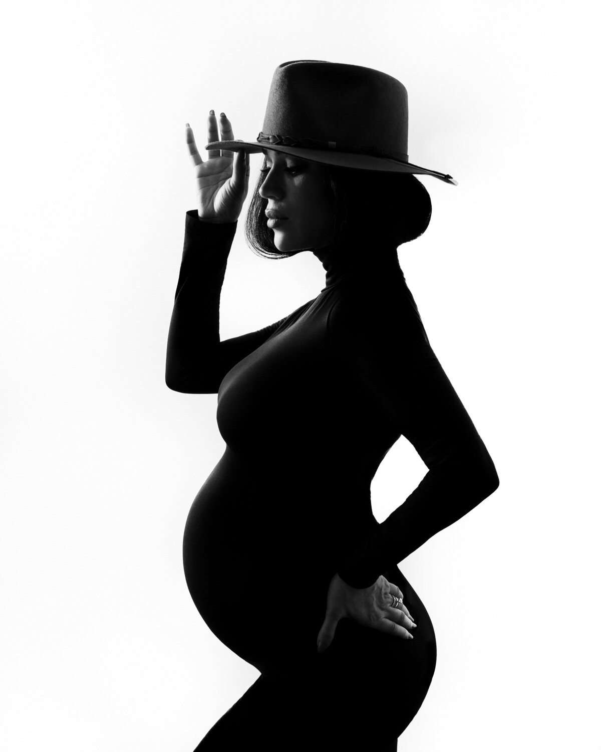 Beautiful black and white silhouette of a pregnant woman wearing a hat by daisy Rey Photography