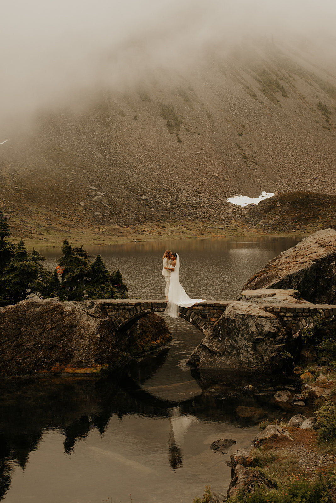 Two brides kissing on bridge near Bagley Lakes during their elopement in the North Cascades!