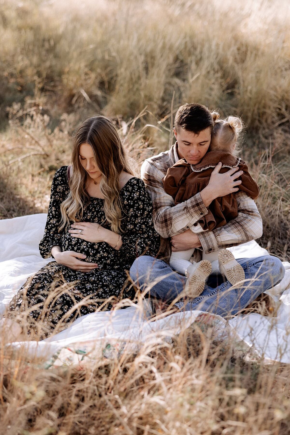 fall maternity session with family sitting on a blanket 