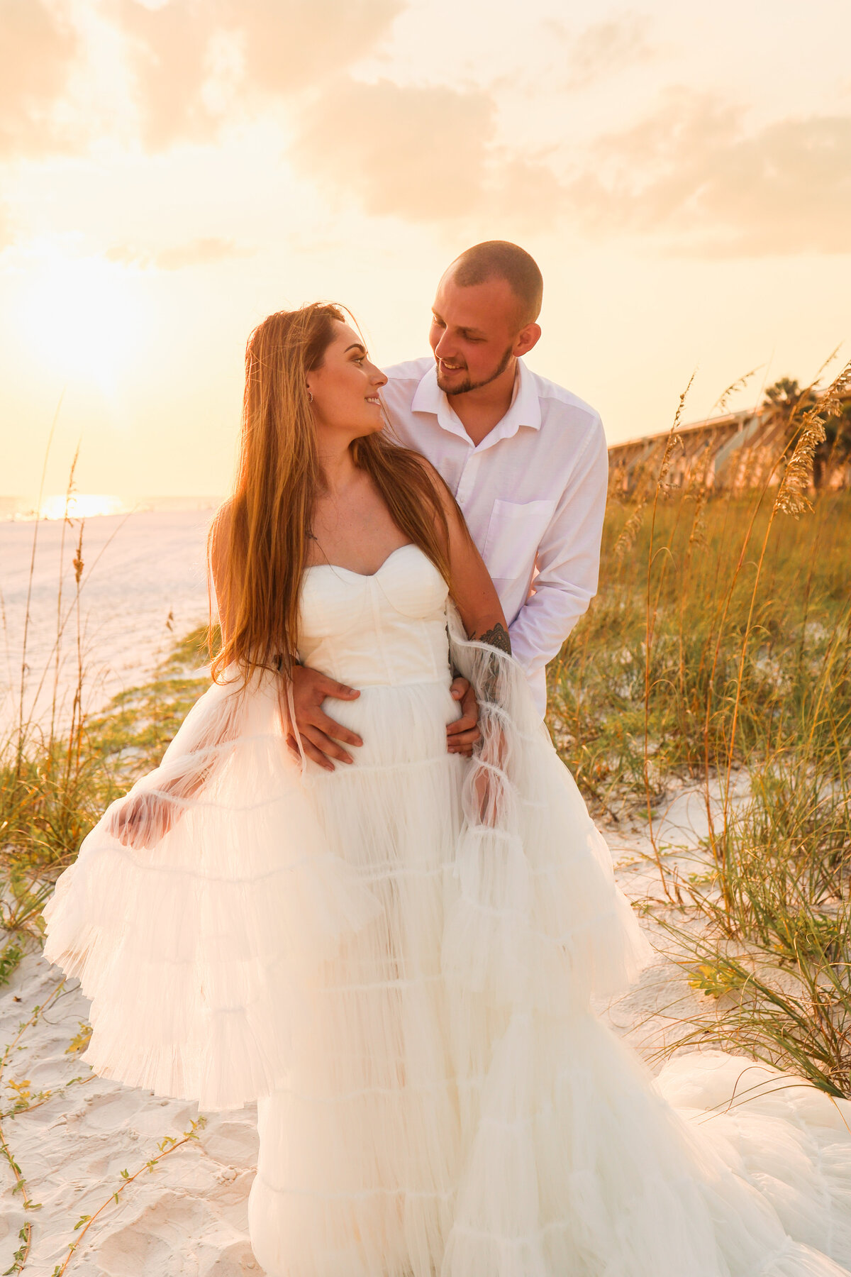 groom and bride standing on beach looking at each other wearing white tulle dress at sunset in Panama City Beach Florida by Florida elopement photographer Amanda Richardson Photography
