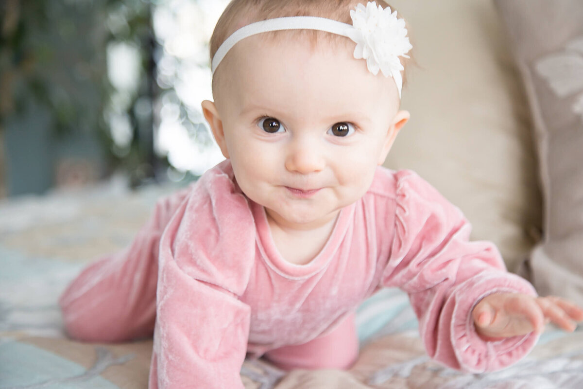 Baby girl excitedly crawling on bed during session with las vegas milestone photographer