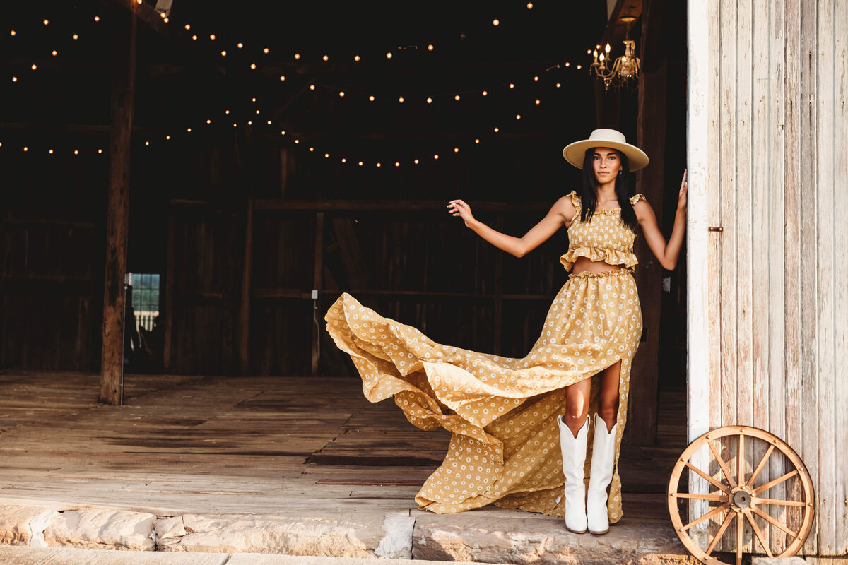 Senior girl standing in barn throwing her dress