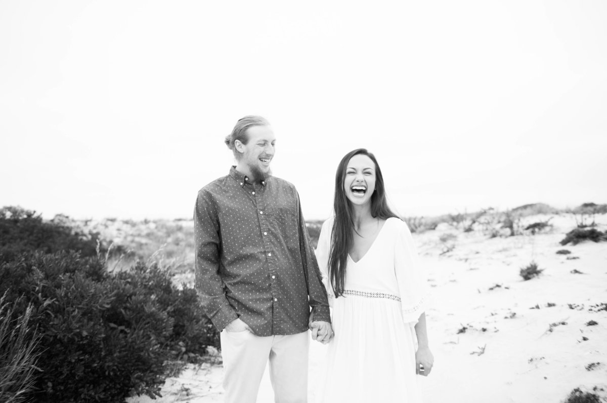 couple laugh and joke during beach engagement photos