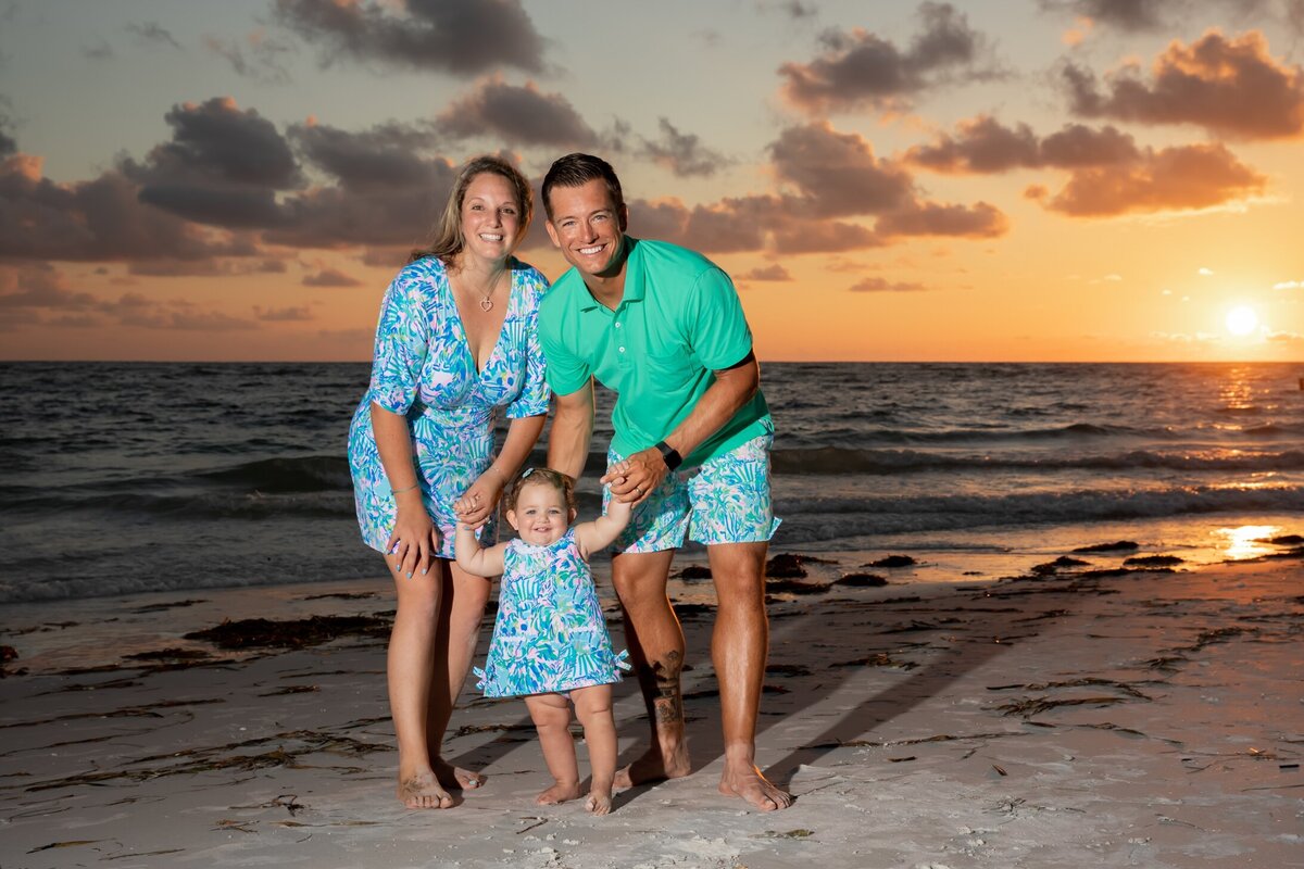 Family of three wearing Lily Pulitzer on the beach at sunset