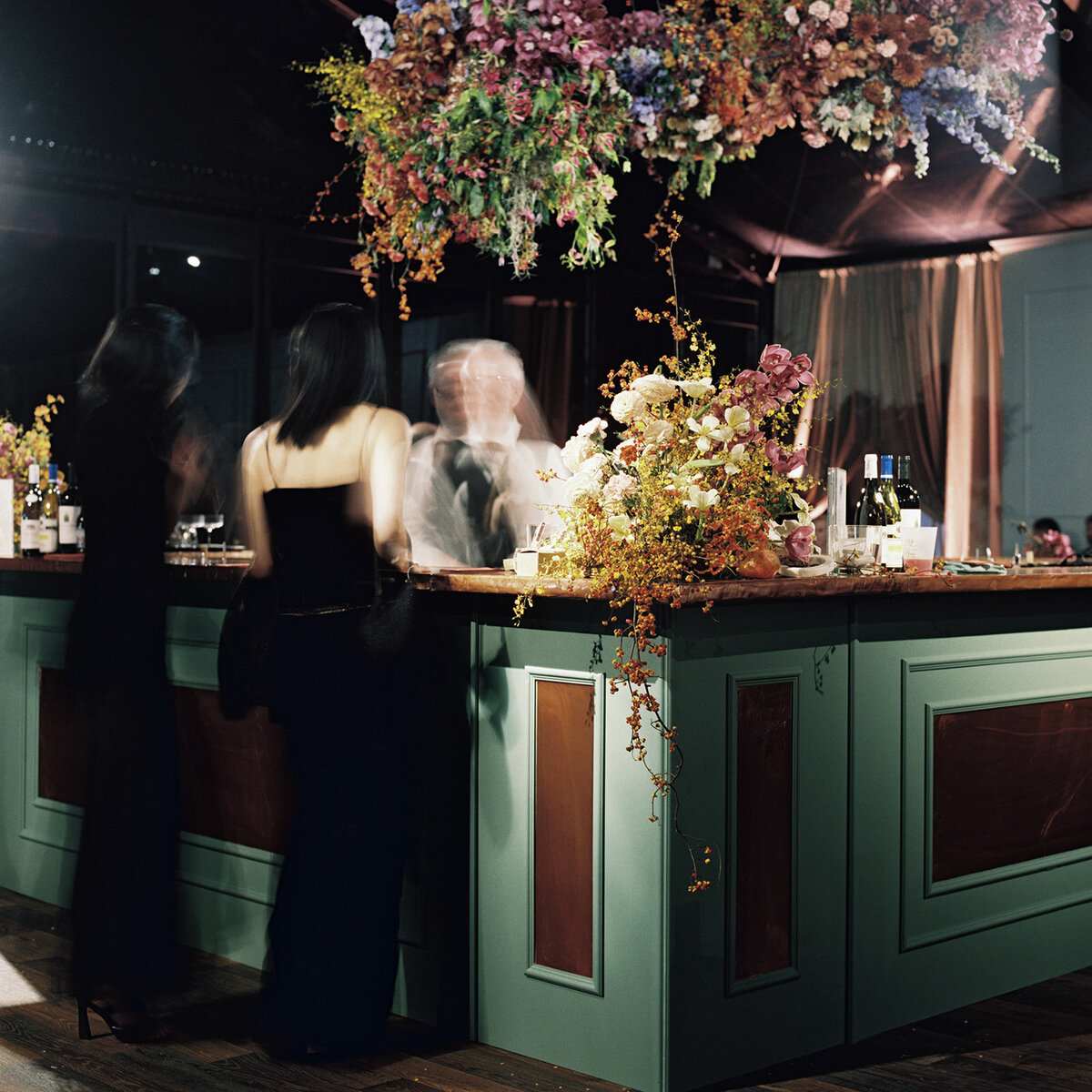 Interacting and sculptural floral clouds hang over the dance floor and bars of this fall wedding reception in Tennessee. Clear top tent build out for fall wedding reception in Tennessee hills.  Product clustered floral clouds in a tasteful fall color palette of copper, ruby, gold, burgundy, rust, and lavender. Orchids, bittersweet berries, butterfly ranunculus, and tulips are highlighted. Unique floral design with flower forward large scale installations. Design by Rosemary & Finch Floral Design in Nashville, TN.