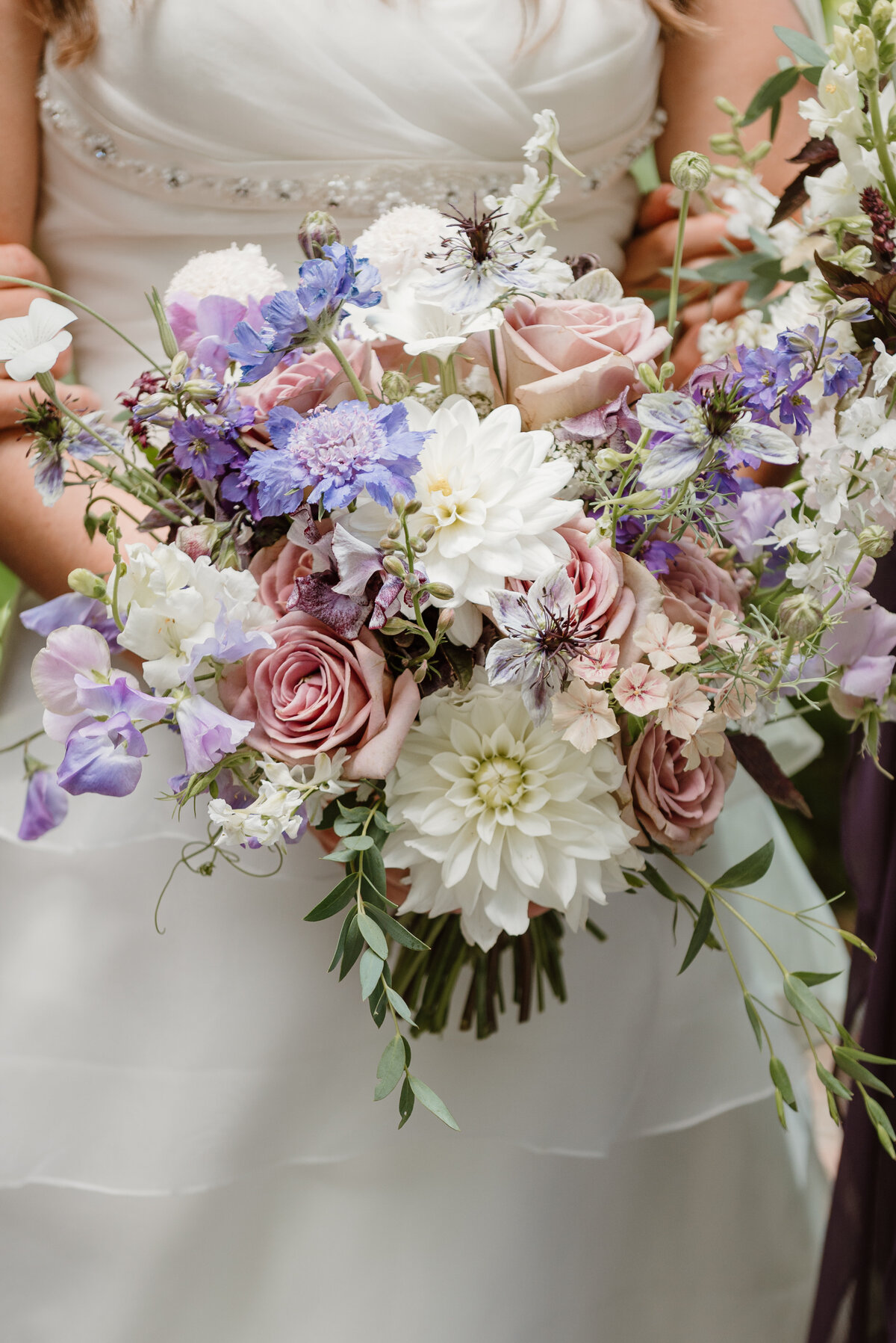 Romantic garden style bridal bouquet featuring dusty lavender roses, white dahlias, lisianthus, scabiosa, nigella, and soft greenery. Designed by Indigo & Violet Co., Bozeman Montana wedding florist.