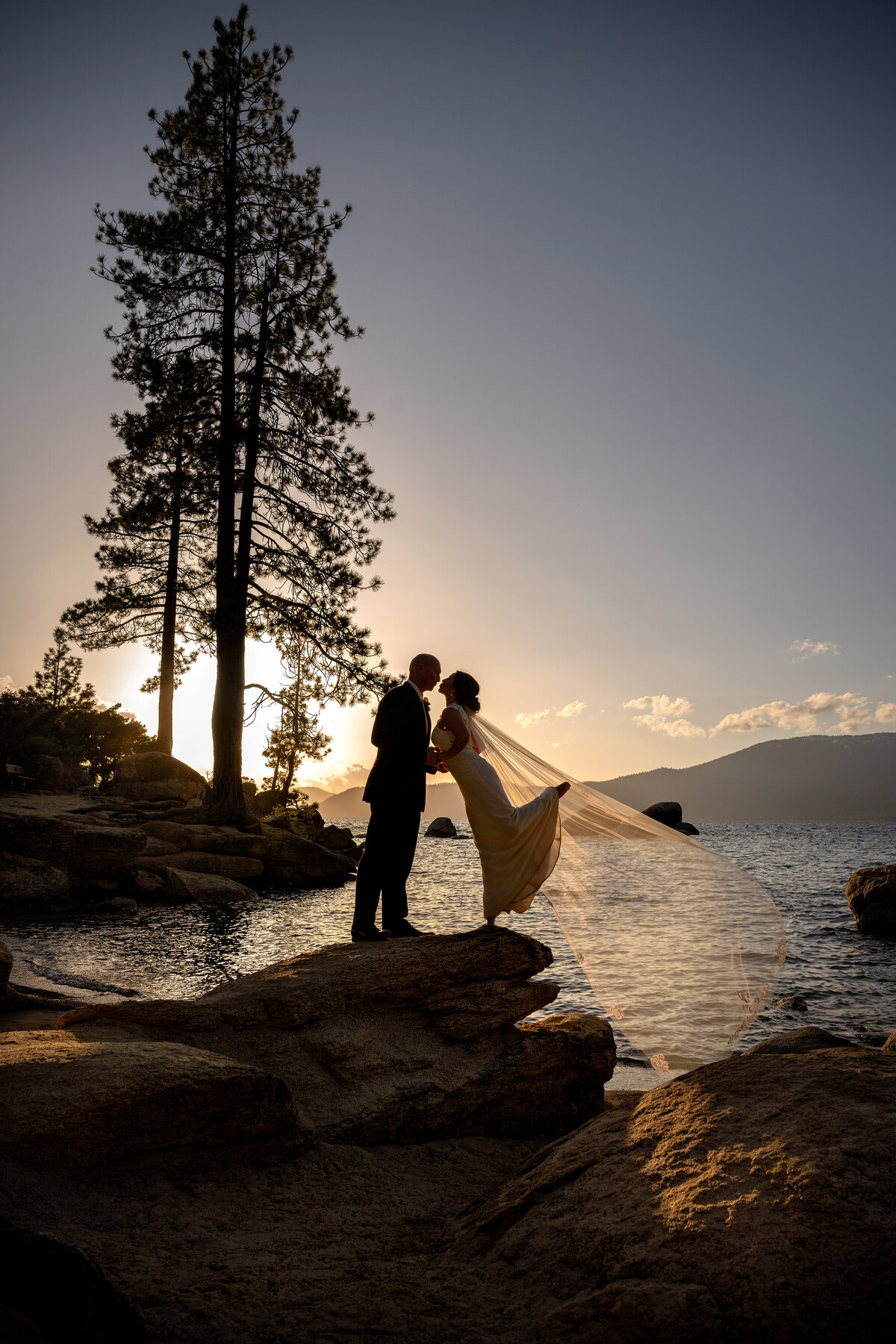 silhouette sunset picture of newlyweds on the rock at Sand Harbor beach Nevada