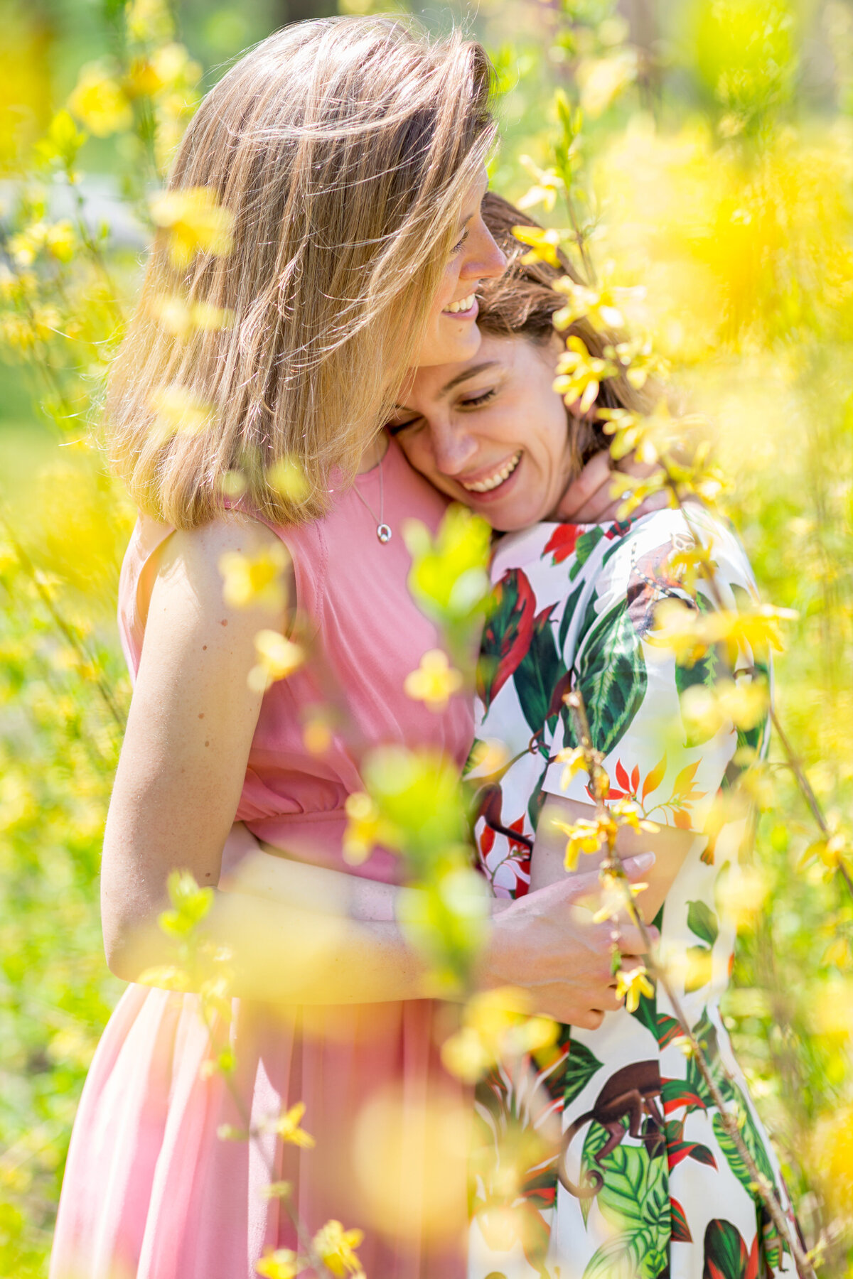 Two brides hugging in a field of tall flowers.