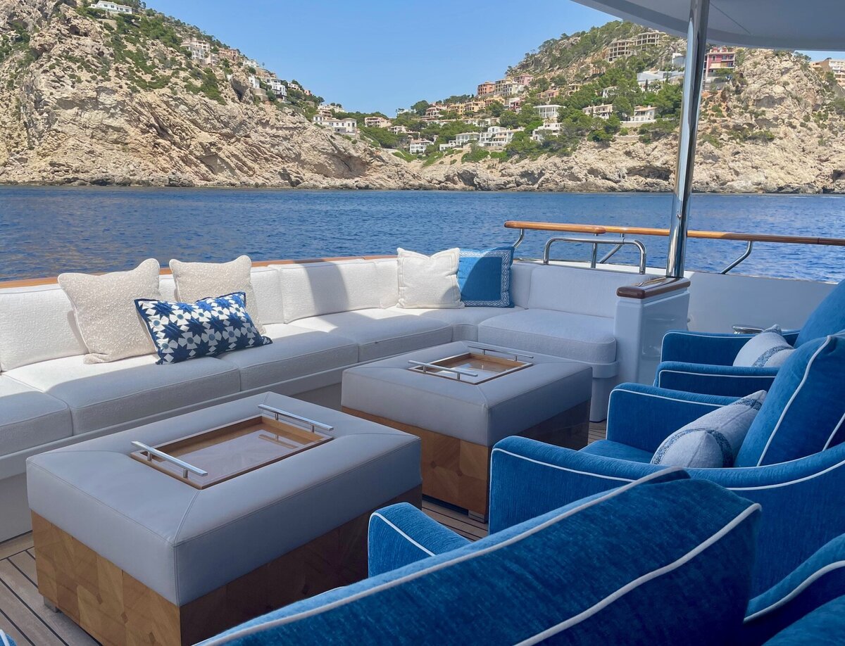 High end yach design featuring white upholstery sectional and blue upholstered chairs overlooking seaside town
