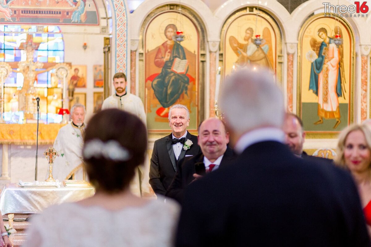Groom stands at the altar watching his Bride being escort up the aisle