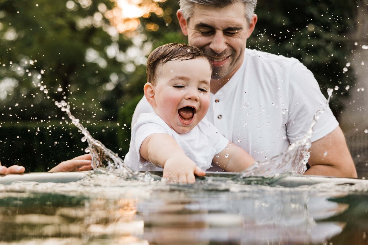 Father and child enjoying playful time with water outdoors during their Pittsburgh family photography session.