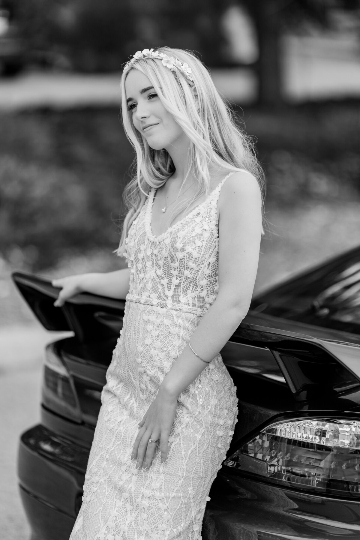 Bride leans against her car for a wedding portrait