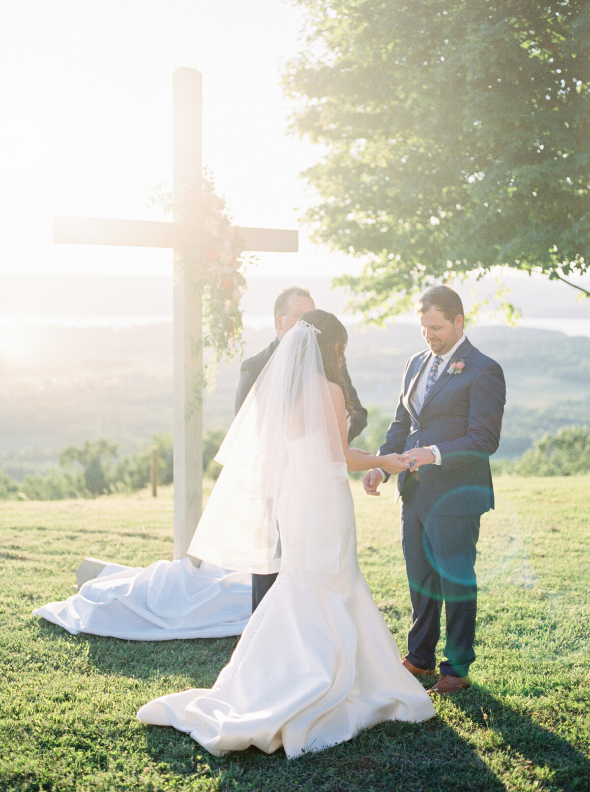 A bride and groom stand in the luminous light in front of their cross as they exchange vows by Huntsville wedding photographer, Kelsey Dawn Photography