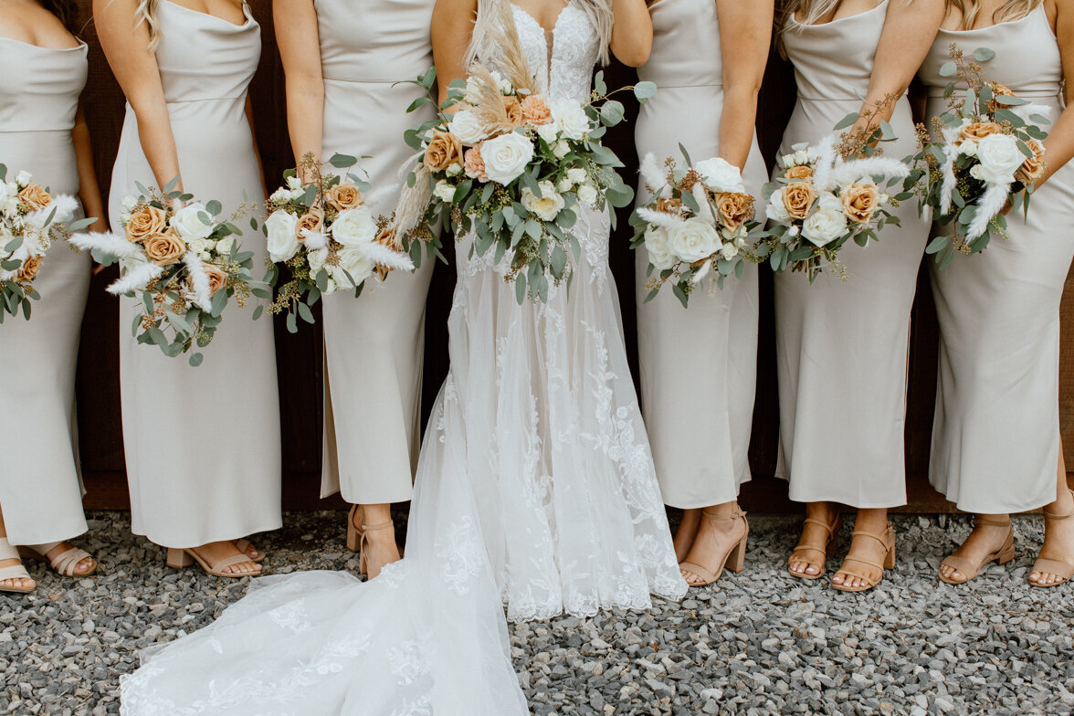 Bridesmaids dressed in Ivory with terra cotta and white floral bouquets.
