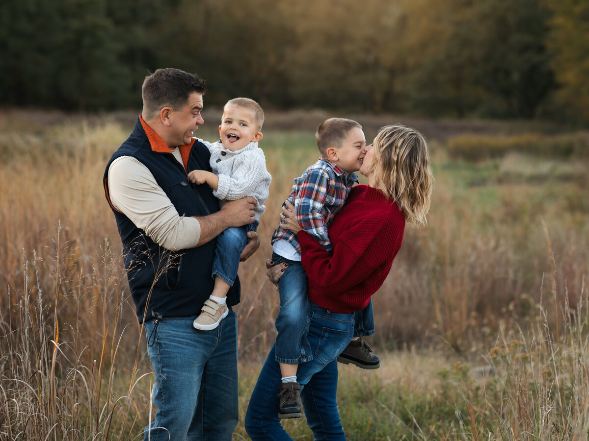 mom dad and two sons posed in field for family photoshoot cleveland family photography