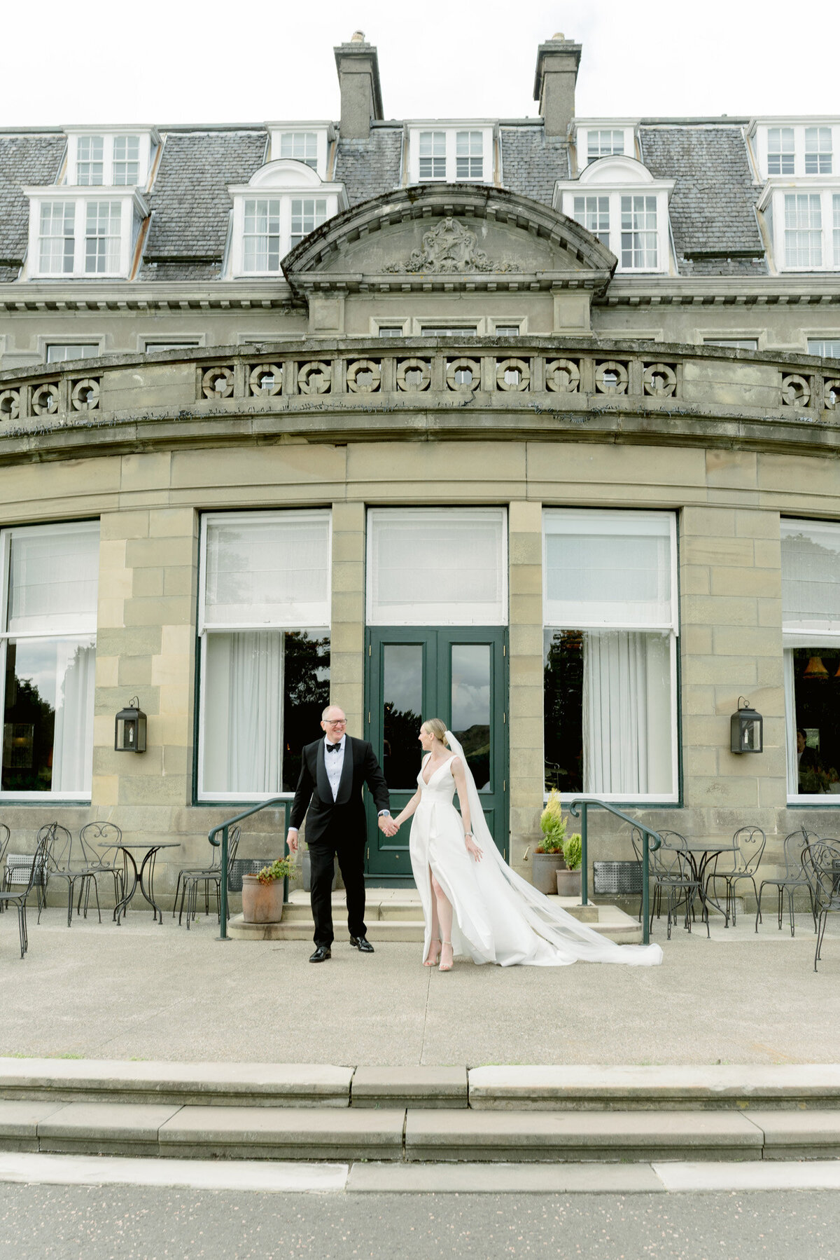 Bride and Groom hand in hand outside Gleneagles Hotel on their wedding day. Image by luxury wedding photographer Scotland, Jill Cherry Porter.
